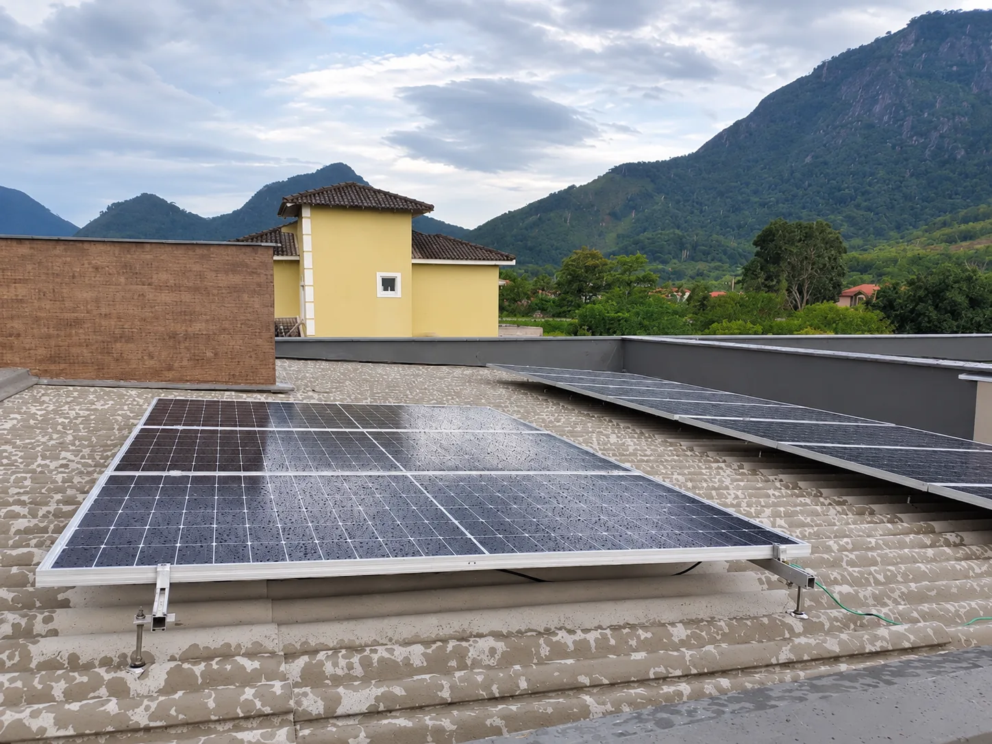 Painéis fotovoltaicos instalados sobre laje, com montanhas ao fundo